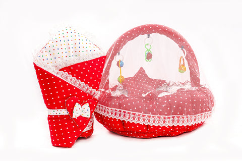 Soft baby snuggle bed with protective net and hanging rattle toys in red polka dot print