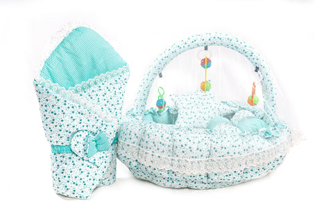 Soft baby snuggle bed with protective net and hanging rattle toys in green flower print