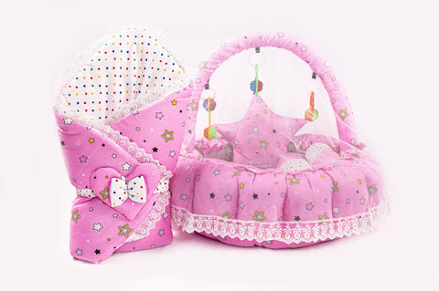 Soft baby snuggle bed with protective net and hanging rattle toys in pink star print