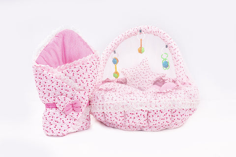 Soft baby snuggle bed with protective net and hanging rattle toys in pink flower print